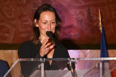 Un groupe de personnes pose devant une bannière, une femme au centre tient un diplôme.