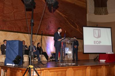 Un groupe de personnes pose devant une bannière, une femme au centre tient un diplôme.