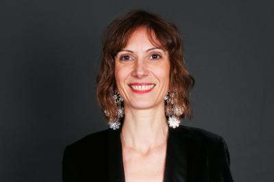 Un groupe de personnes pose devant une bannière, une femme au centre tient un diplôme.