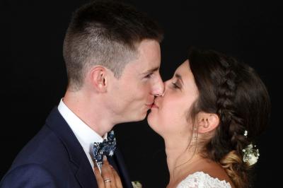 Un couple en tenue de mariage danse sur une place pavée devant un bâtiment historique.