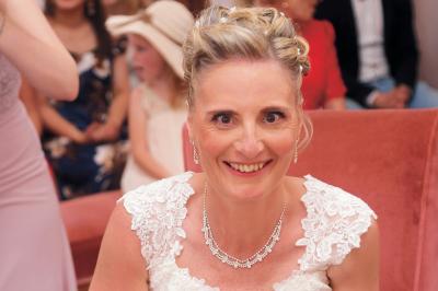 Un couple en tenue de mariage danse sur une place pavée devant un bâtiment historique.