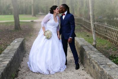 Un couple en tenue de mariage danse sur une place pavée devant un bâtiment historique.