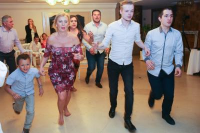 Un couple en tenue de mariage danse sur une place pavée devant un bâtiment historique.