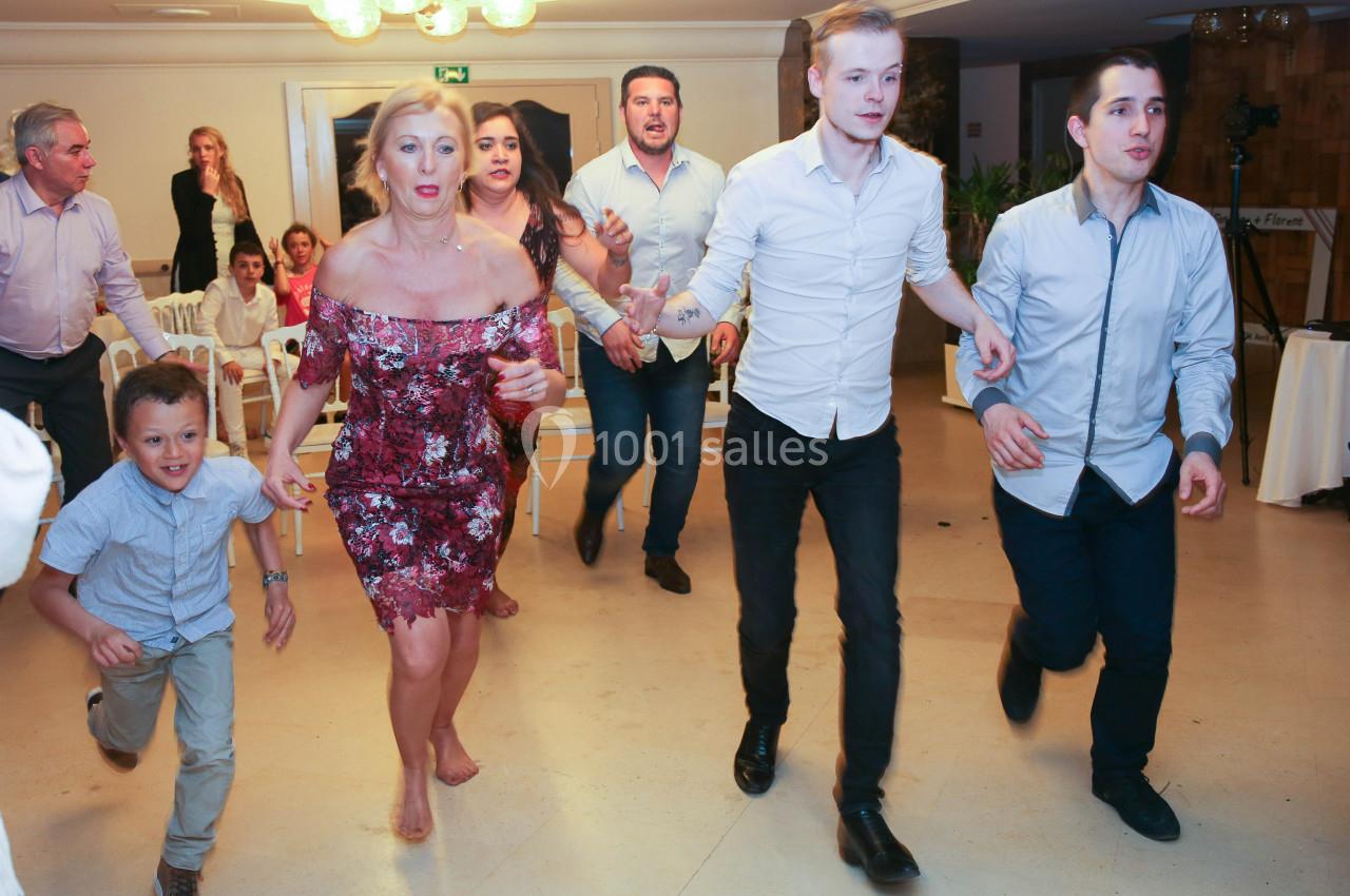 Des personnes de tous âges courent ensemble dans une salle lumineuse, semblant participer à une activité festive.