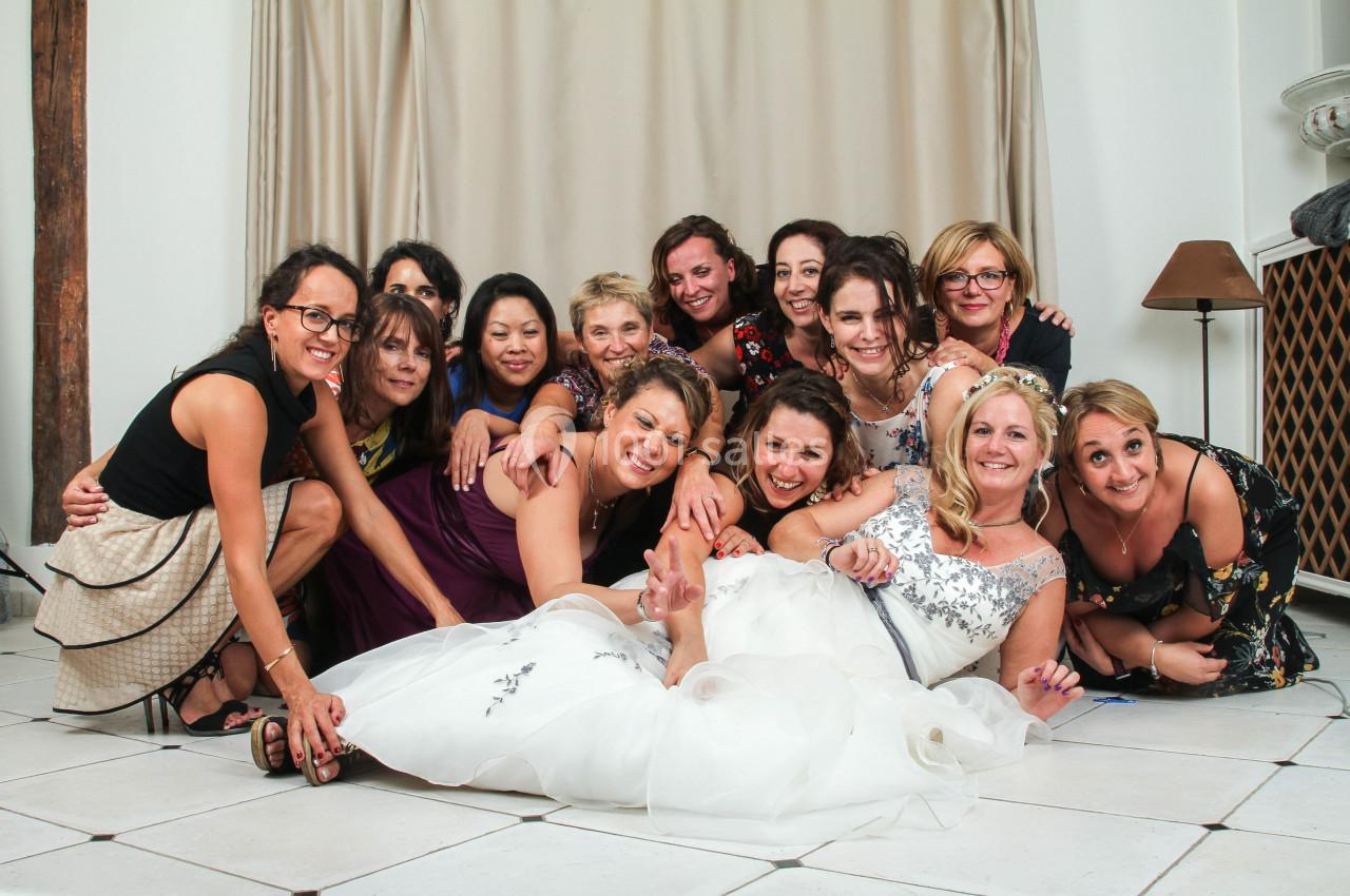 Un groupe de femmes souriantes posant ensemble, certaines assises et d'autres allongées sur le sol, dans une salle lumineuse.