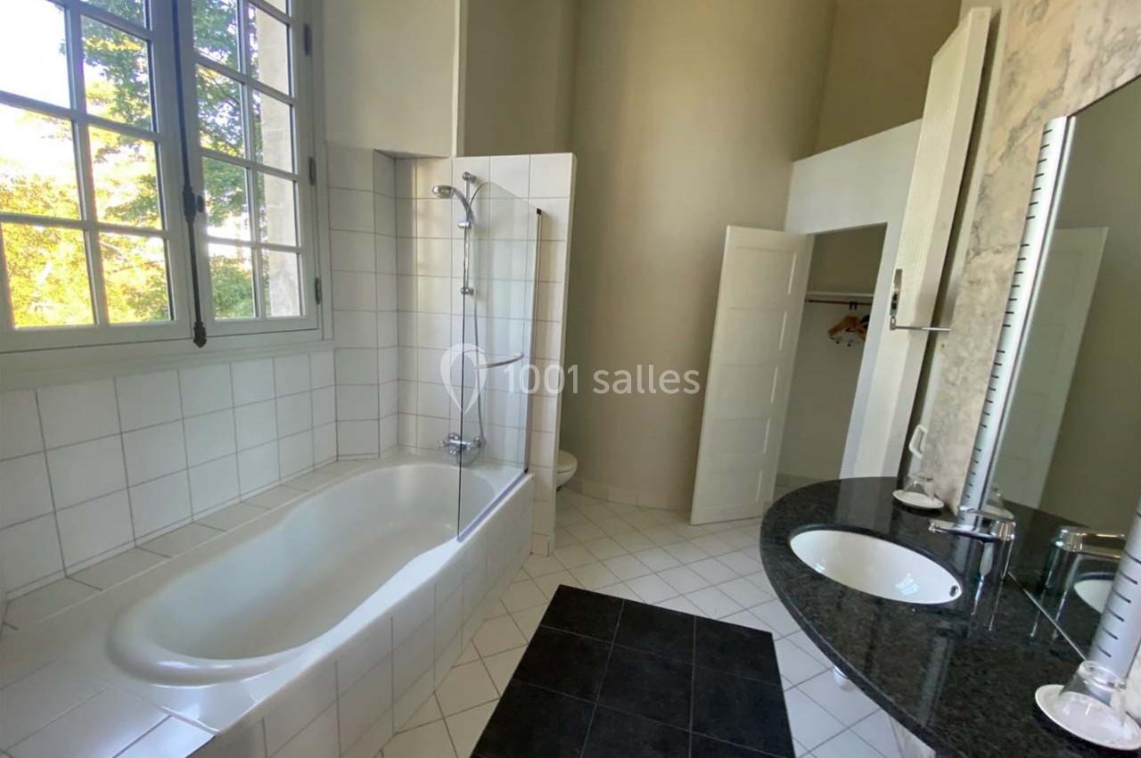 Salle de bain lumineuse avec baignoire, douche intégrée, lavabo sur plan en marbre et fenêtre donnant sur l'extérieur.