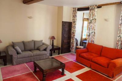 Vase de pivoines roses sur une table en bois, entouré de livres, chandeliers et fauteuils dans un salon élégant.