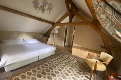 Vase de pivoines roses sur une table en bois, entouré de livres, chandeliers et fauteuils dans un salon élégant.