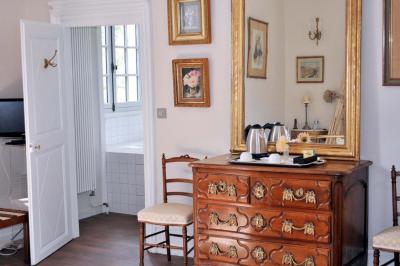 Vase de pivoines roses sur une table en bois, entouré de livres, chandeliers et fauteuils dans un salon élégant.