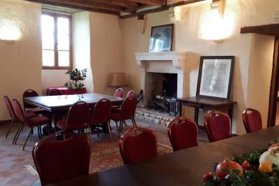 Vase de pivoines roses sur une table en bois, entouré de livres, chandeliers et fauteuils dans un salon élégant.