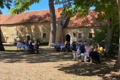 Vase de pivoines roses sur une table en bois, entouré de livres, chandeliers et fauteuils dans un salon élégant.