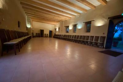 Vase de pivoines roses sur une table en bois, entouré de livres, chandeliers et fauteuils dans un salon élégant.