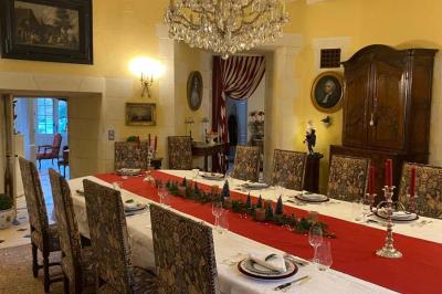 Bâtiment en pierre avec toit en tuiles rouges, entouré d'arbres et d'une pelouse, sous un ciel partiellement nuageux.