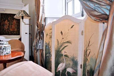 Bâtiment en pierre avec toit en tuiles rouges, entouré d'arbres et d'une pelouse, sous un ciel partiellement nuageux.