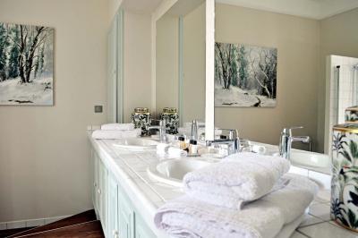 Bâtiment en pierre avec toit en tuiles rouges, entouré d'arbres et d'une pelouse, sous un ciel partiellement nuageux.