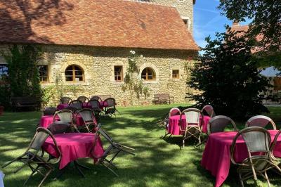 Bâtiment en pierre avec toit en tuiles rouges, entouré d'arbres et d'une pelouse, sous un ciel partiellement nuageux.