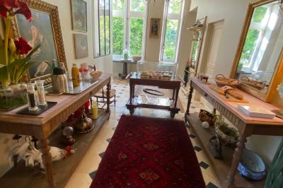 Bâtiment en pierre avec toit en tuiles rouges, entouré d'arbres et d'une pelouse, sous un ciel partiellement nuageux.