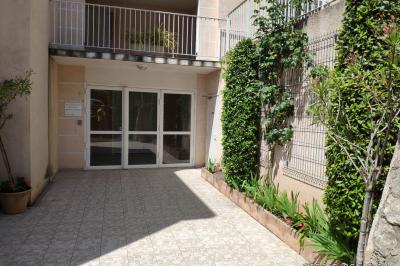 Parking extérieur de nuit avec une voiture stationnée, éclairé par des lampadaires et entouré de haies et d'arbres.