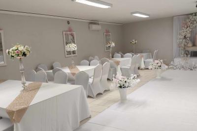 Parking extérieur de nuit avec une voiture stationnée, éclairé par des lampadaires et entouré de haies et d'arbres.