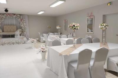 Parking extérieur de nuit avec une voiture stationnée, éclairé par des lampadaires et entouré de haies et d'arbres.