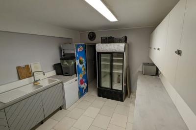 Parking extérieur de nuit avec une voiture stationnée, éclairé par des lampadaires et entouré de haies et d'arbres.