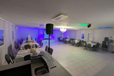 Parking extérieur de nuit avec une voiture stationnée, éclairé par des lampadaires et entouré de haies et d'arbres.