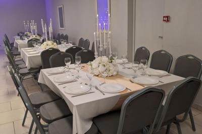 Parking extérieur de nuit avec une voiture stationnée, éclairé par des lampadaires et entouré de haies et d'arbres.