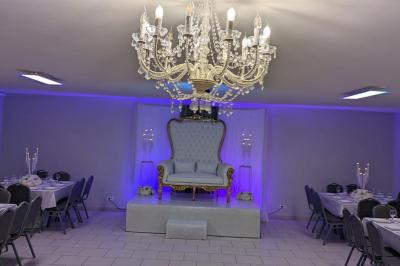 Parking extérieur de nuit avec une voiture stationnée, éclairé par des lampadaires et entouré de haies et d'arbres.