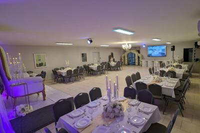 Parking extérieur de nuit avec une voiture stationnée, éclairé par des lampadaires et entouré de haies et d'arbres.