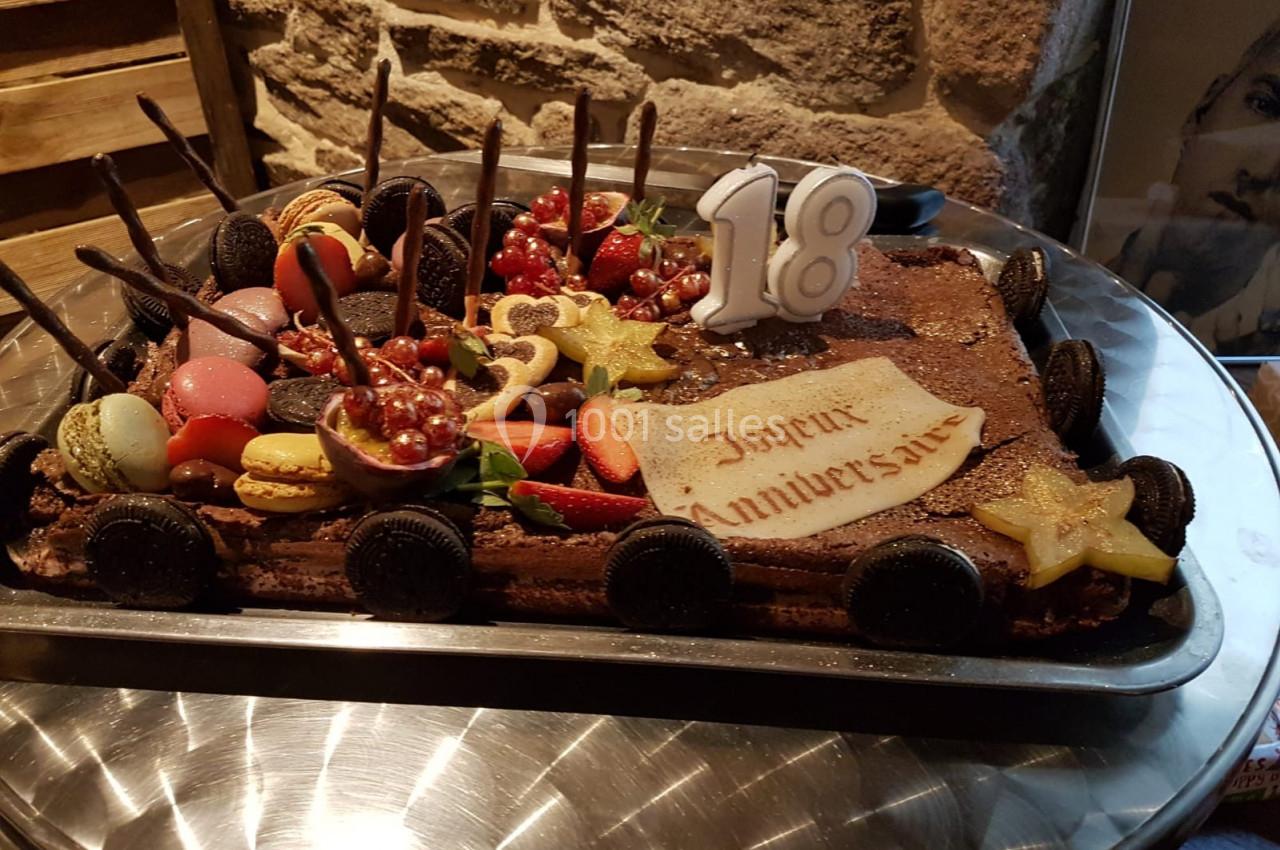 Gâteau d'anniversaire décoré de fruits, macarons, biscuits et bougies en forme de chiffre 18.