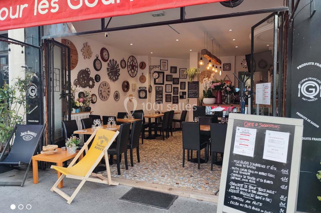 Salle de restaurant avec décoration murale éclectique, terrasse extérieure avec chaise longue et ardoise de menu.