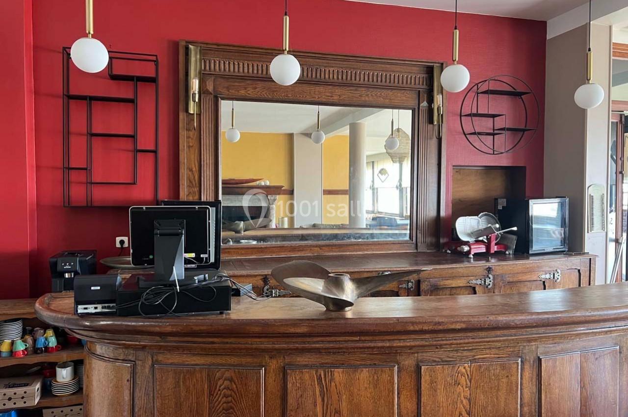 Comptoir en bois ancien avec miroir encadré, décoré de luminaires suspendus et étagères murales modernes.