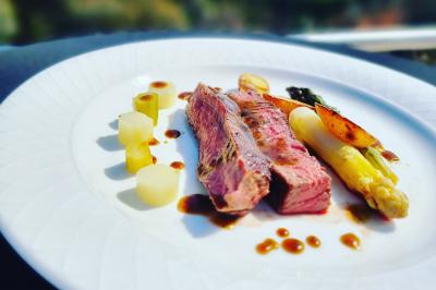 Assiette de légumes variés dressés avec soin, comprenant asperges, carottes, chou-fleur, roquette et sauce décorative.