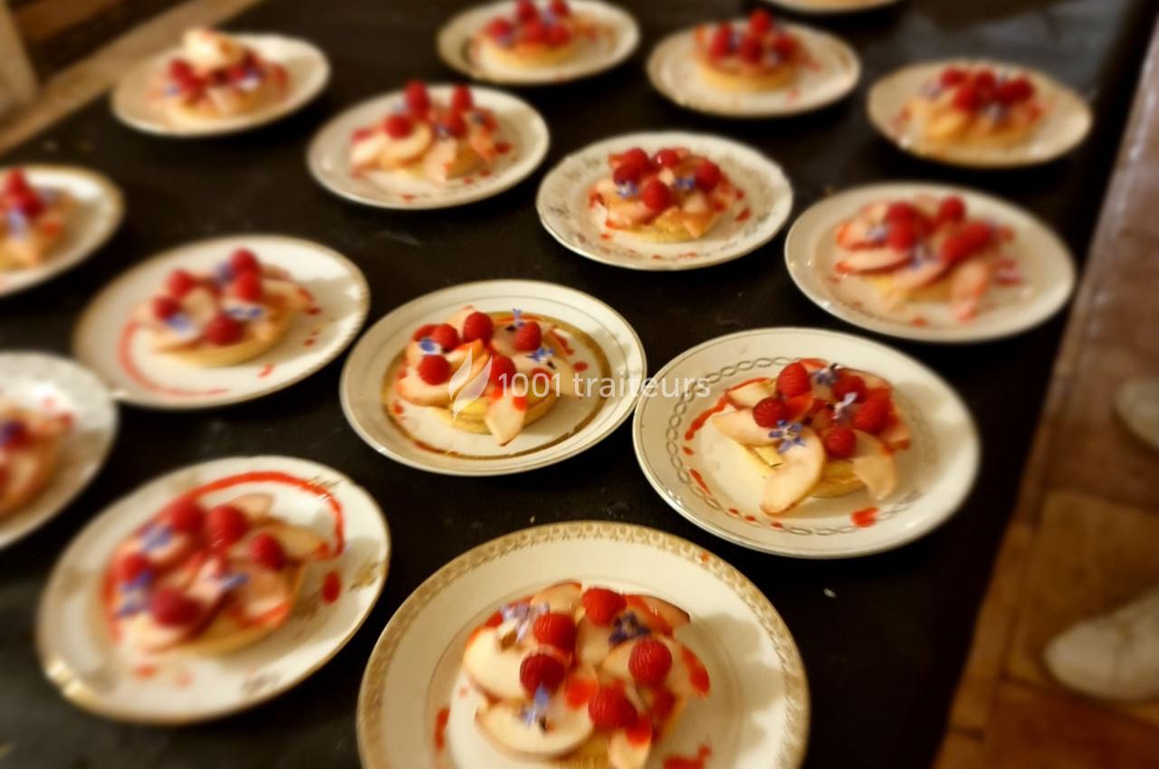 Assiettes de desserts garnis de fruits rouges et de coulis, disposées sur une table sombre.