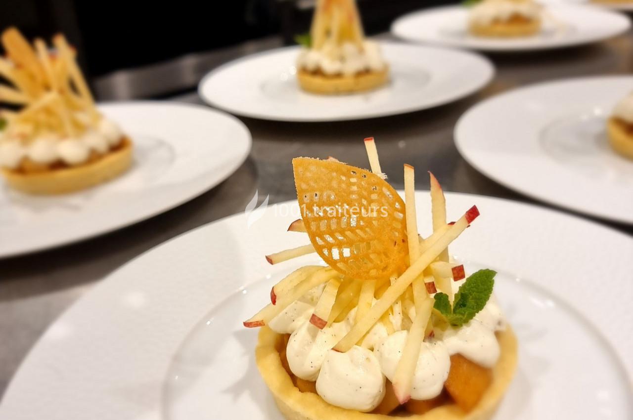 Tartelette garnie de crème, pommes en julienne et décor croustillant, servie sur une assiette blanche.