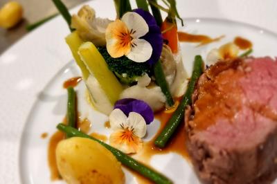 Assiette de légumes variés dressés avec soin, comprenant asperges, carottes, chou-fleur, roquette et sauce décorative.