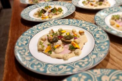 Assiette de légumes variés dressés avec soin, comprenant asperges, carottes, chou-fleur, roquette et sauce décorative.