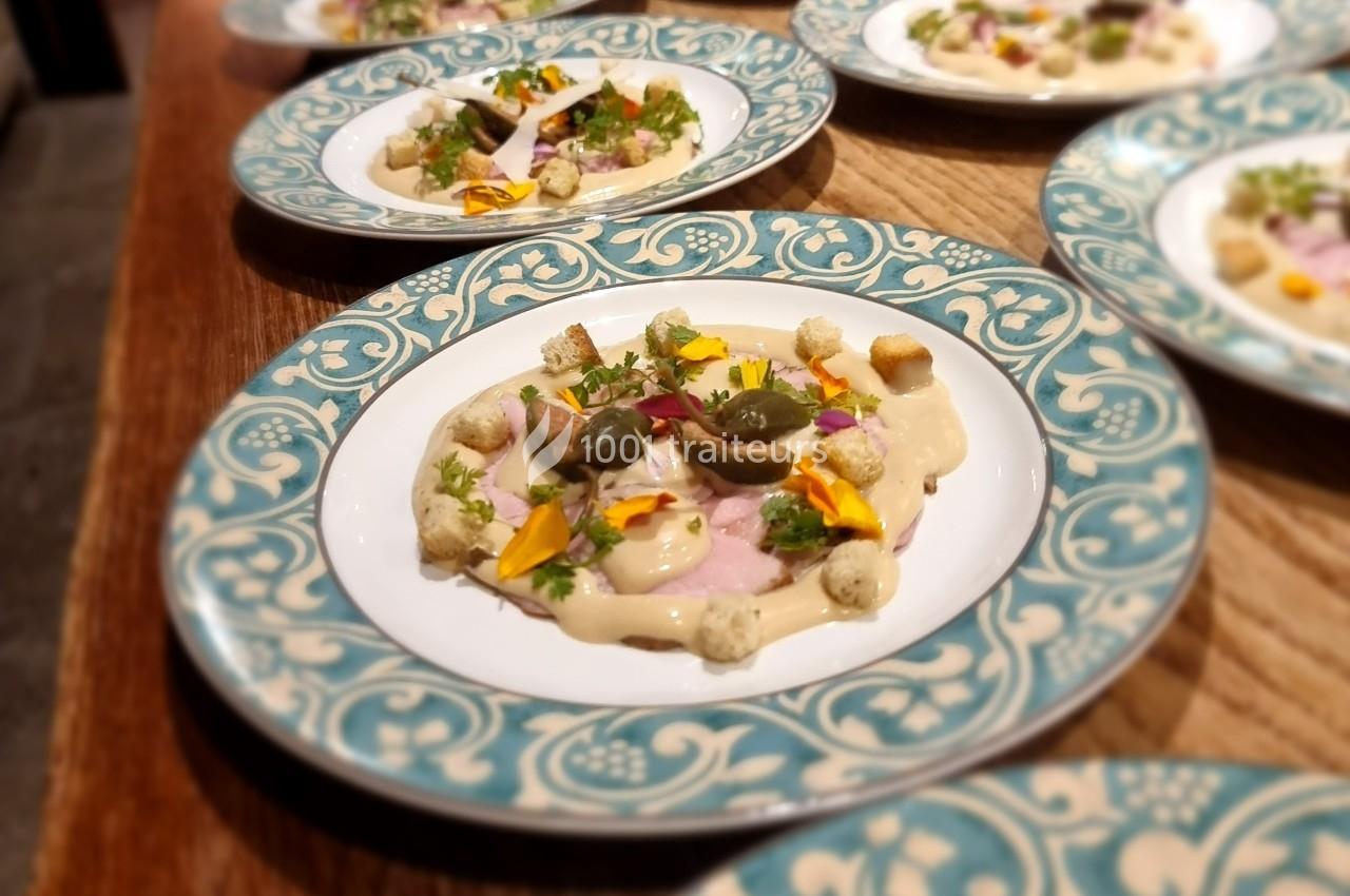 Assiette décorée contenant une présentation soignée de mets avec des fleurs comestibles, croûtons et garnitures.