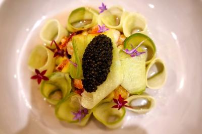 Assiette de légumes variés dressés avec soin, comprenant asperges, carottes, chou-fleur, roquette et sauce décorative.