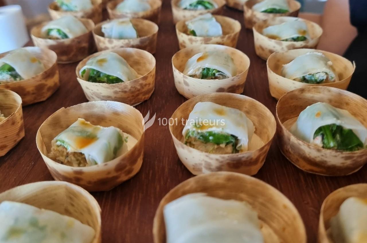 Assortiment de bouchées dans des coupelles en bambou, garnies de légumes et enveloppées dans une fine pâte blanche.