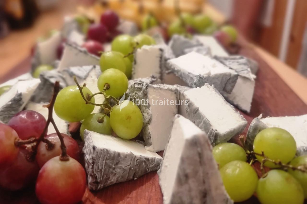 Assortiment de fromages à pâte molle avec croûte cendrée, accompagné de raisins verts et rouges sur une planche en bois.