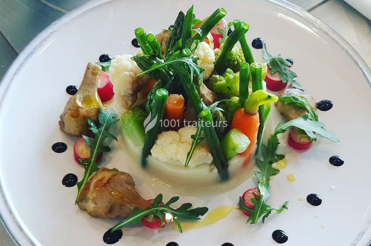 Assiette de légumes variés joliment dressés avec des touches de sauce et des décorations de roquette.