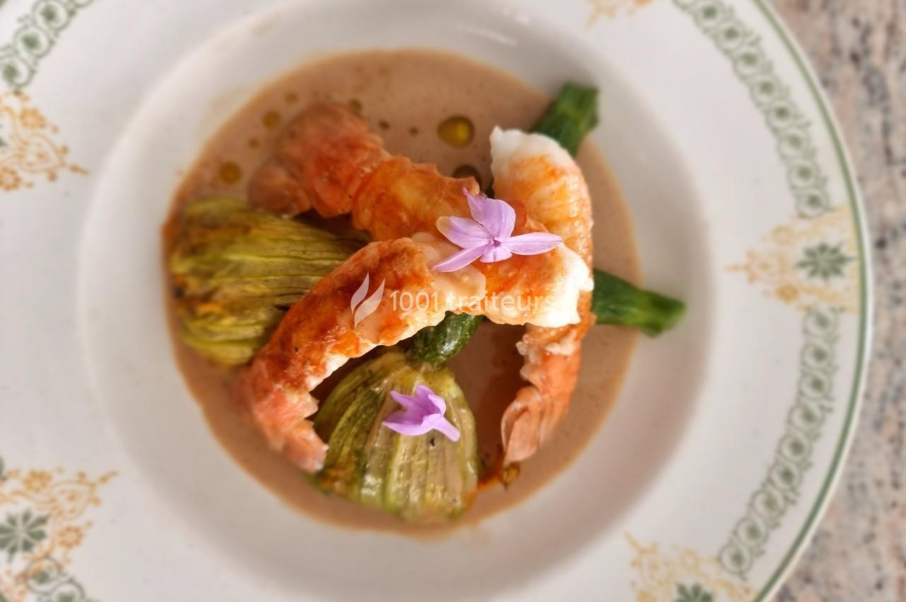 Assiette gastronomique avec fleurs de courgettes farcies, langoustines et sauce, décorée de fleurs comestibles.