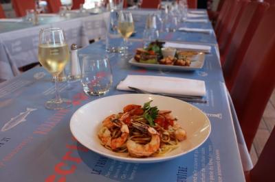 Des personnes se servent à un buffet en plein air, avec un chef en tenue blanche préparant des plats.