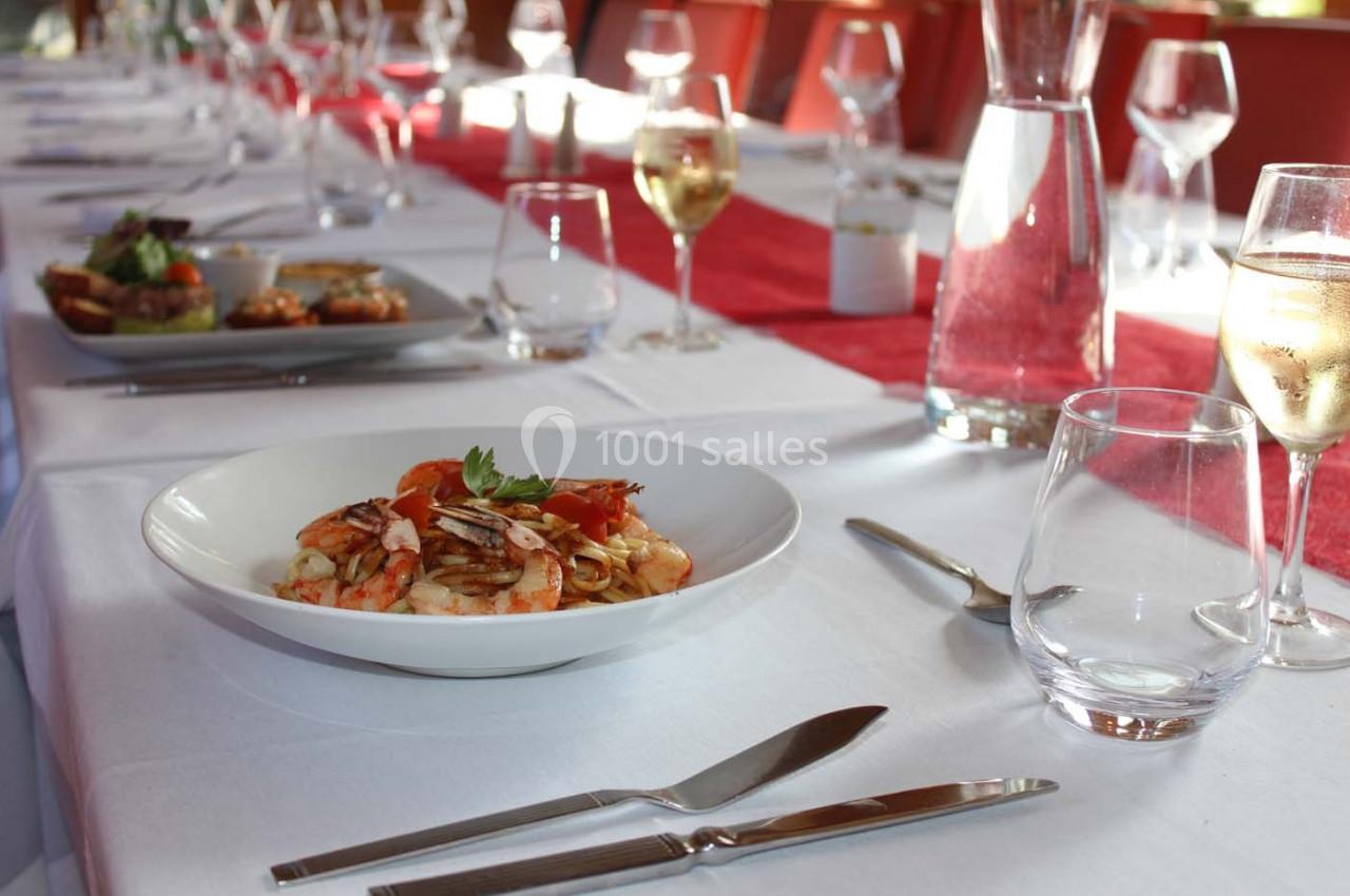 Assiette de fruits de mer sur une table dressée avec nappes blanches, couverts, verres et carafes.