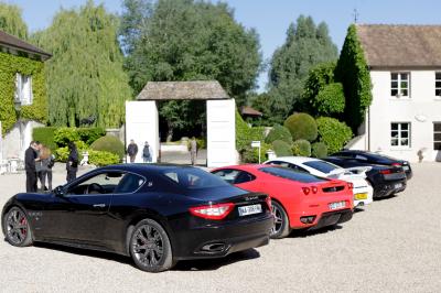 Un homme en costume noir et baskets blanches pointe du doigt sur une scène éclairée par des projecteurs.