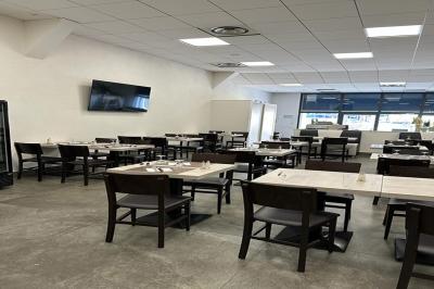 Terrasse ombragée avec des canisses, entourée de bâtiments et d'une structure bleue moderne en arrière-plan.