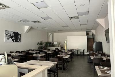 Terrasse ombragée avec des canisses, entourée de bâtiments et d'une structure bleue moderne en arrière-plan.