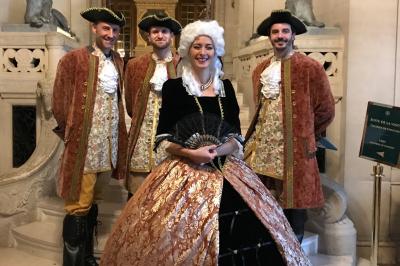 Miniature Chasse au trésor historique Deux personnes assises dans un buggy bleu en extérieur, discutant et manipulant des objets, avec un homme debout à côté.