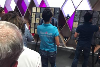 Miniature Chasseurs de trésor Deux personnes assises dans un buggy bleu en extérieur, discutant et manipulant des objets, avec un homme debout à côté.